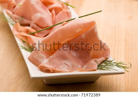 photo of thin slices of italian mortadella called also bologna on small rectangular plate served as appetizer