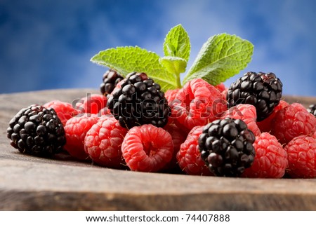 photo of delicious berries with meant leaves on wooden table