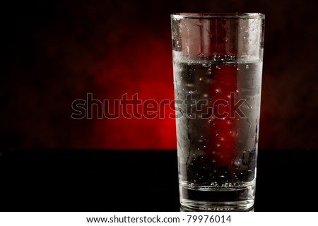 photo of a water glass with sparkling cold water inside on black glass table