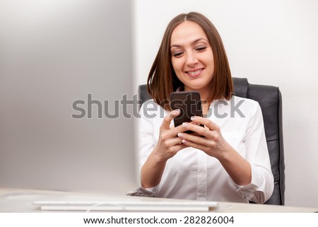 Businneswoman is writing an email from her mobile phone in office