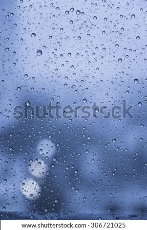Raindrops over the window with blurred background in vintage blue sad tone