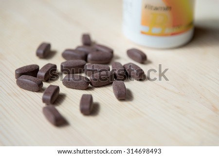 Pills of medicine or vitamin as capsules on wood background in natural light