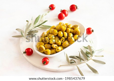 Grilled green olives. Tasty organic green olives in the plate. Olive on marble floor