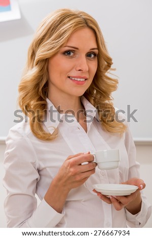 Cute girl drinks coffee. Attractive blonde with a cup of coffee. Business woman.