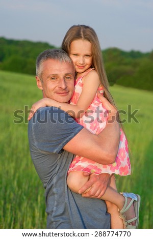 Dad hugs daughter in his arms. Father and daughter in the field.
