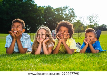 Four happy children are laying in a garden and looking around with interest.