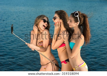 Young girls make selfie at rest. Girls on the beach. Young people at the resort. Leisure at sea. Girls sunbathing on the sea.