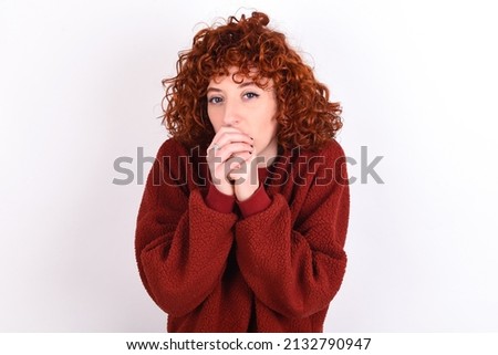 young redhead girl wearing red sweater over white background holding oneself, feels very cold outside, hopes that will not get cold 商業照片 © 
