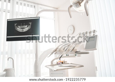Interior of modern dentist cabinet and medical chair. Stomatology cabinet with nobody in it and white equipment for oral treatment. Interiors concept ストックフォト © 