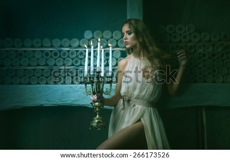 sexy brunette girl holding a candelabra with candles. women\'s mystique and mystery. in the background, wine cellar