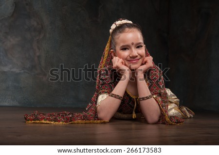 schoolgirl learns Indian dance. Sitting on a stone and repeats the motion, dressed in traditional costume