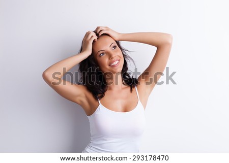 Attractive girl is smiling and expressing happiness. Her hands are on the top of her head. She is looking up with joy. Isolated