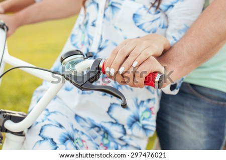 Close up of hands of loving couple riding bicycle together. Their hands are on handlebar