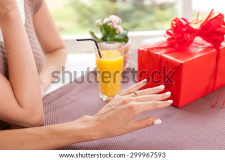 Close up of hand of girl boasting and showing the ring to her friend. There is a gift on the table