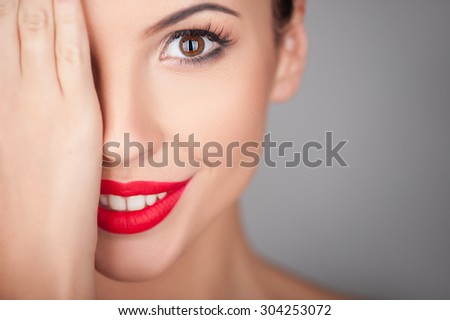Attractive woman is covering her right eye with her palm. She is smiling and looking forward with joy. Isolated and copy space in right side