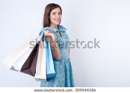 Attractive girl is standing and holding many packages of bought things. She is going shopping with enjoyment. The lady is looking at the camera and smiling. Isolated and copy space in right side