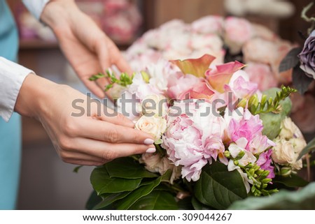 Close up of arms of skilled saleswoman making beautiful bouquet in workshop