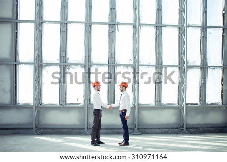 Cheerful architect and a foreman are shaking hands. They made a deal. The men are smiling and looking at each other with trust. Copy space in right and left side