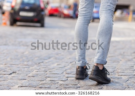 Close up of legs of man walking on street. He is making his travel across city. Copy space in left side