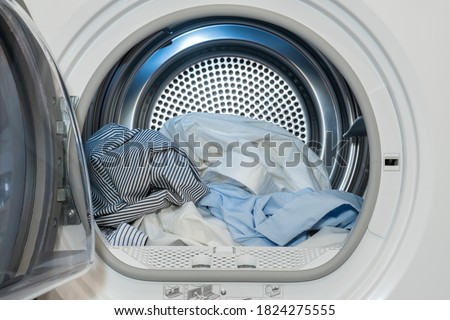 Close up view on clothes dryer with washed and dried shirts in and door open.