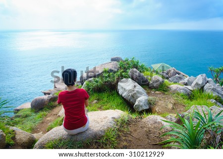 The girl on the cape point/Phu Yen, VietNam  March 29th 2015: At the morning, this girl who wears red T-shirt, is sitting at Dai Lanh cape point, Easternmost of VietNam, PhuYen, VietNam