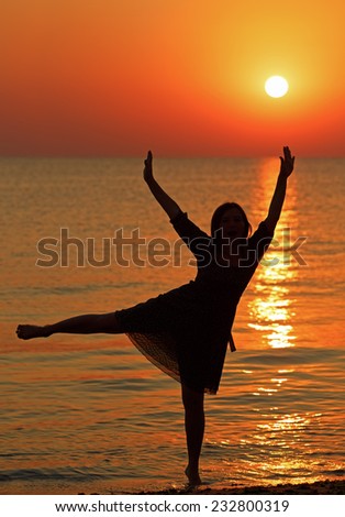 Girl dancing on the background of sunrise over the sea. Shallow depth of field.