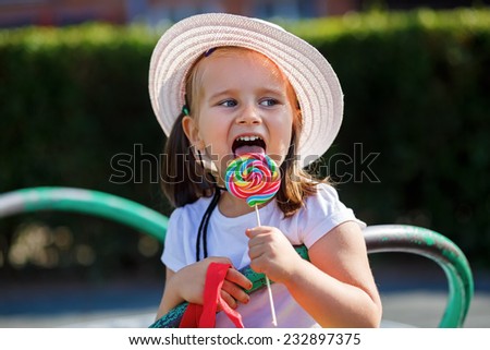 Little girl eating big candy. Shallow depth of field.