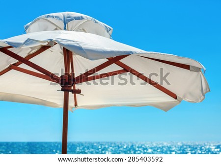 Big white parasol on a background of bright blue sky close-up. Beach umbrella.