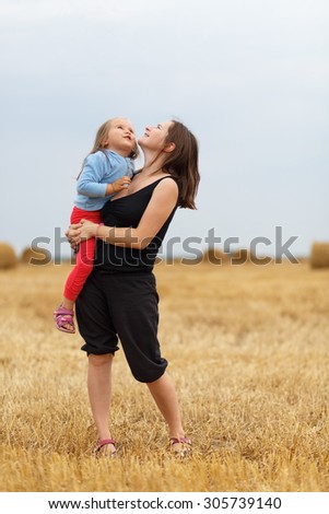 Mother and baby daughter in his arms in the straw field. Shallow depth of field. Selective focus.