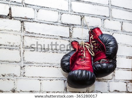 A pair of old boxing gloves hanging on white brick wall background. Zdjęcia stock © 
