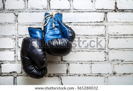 Pair of old blue boxing gloves hanging on white brick wall background. Zdjęcia stock © 
