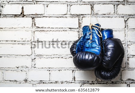 Pair of old blue and black boxing gloves hanging on white brick wall. Zdjęcia stock © 