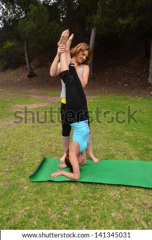 Woman doing outdoor yoga/Outdoor Yoga.Two woman are engaged in yoga in outdoor setting