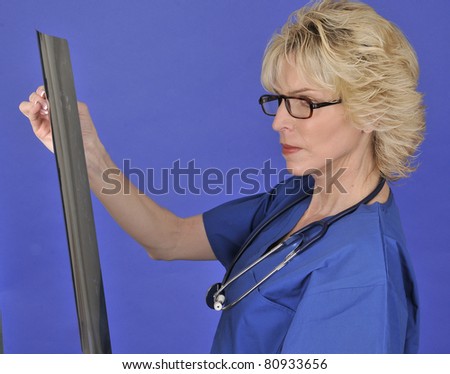 Woman holding CT scan/Woman in Medicine/Woman wearing scrubs inspects CT scan