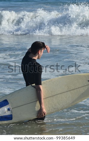 Young Man preparing to surf/Surfs Up!/ Man going out to the surf
