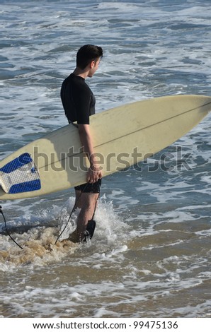 Surfer board and ocean/Surfs Up/Surfer wading into the ocean