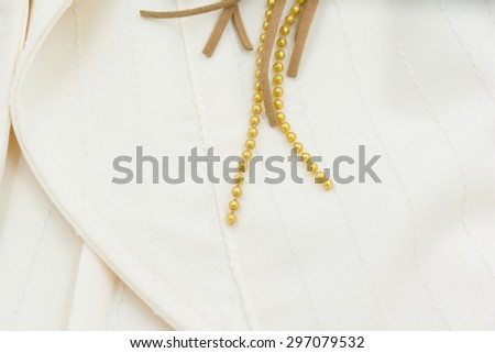 Grass beads and line of brown leather decorate on cream-color shirt