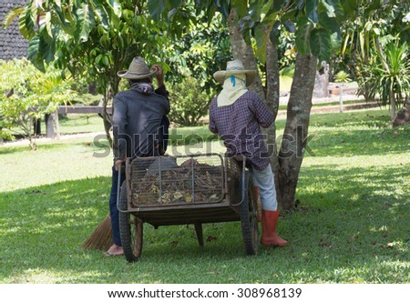 Two picking up garbage man take a rest  by sitting on tray fill with dry leave