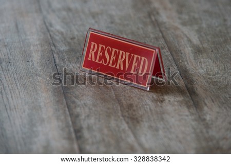 Red acrylic reserved sign on wooden table