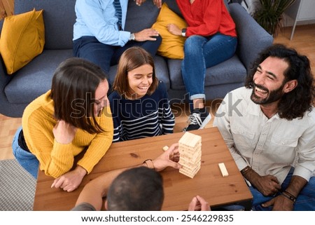 Similar – Image, Stock Photo Excited girl playing jenga game with her mom in play room. Girl removing one block from stack and placing it on top of tower. Game of skill and fun. Family time