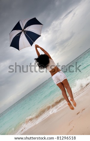 Tanned woman jump with umbrella in blue sea under grey cloud sky