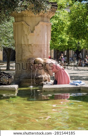 CORDOBA - SPAIN - MAY 09, 2015 - Woman drinking water and cooling from a source a hot day in Cordoba, Spain. The city of Cordoba it is located in the autonomous region of Andalucia in southern Spain