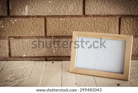 Photo frame on wooden table over wall background - Still life and vintage style