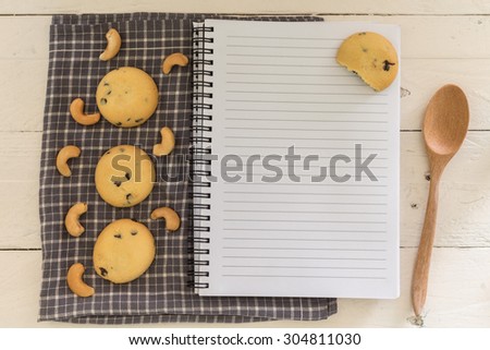Recipe book with cookie on wooden background