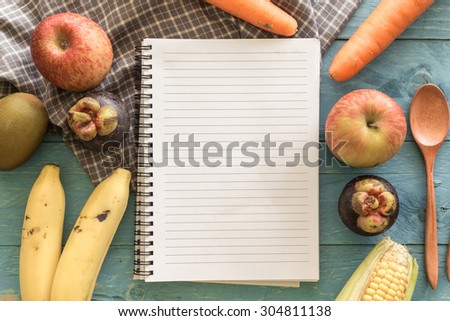 Recipe book with fruits on wooden background