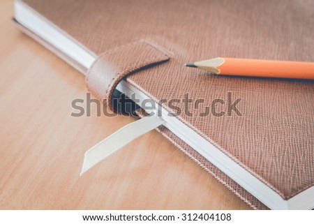 Book and pencil on wooden table background - vintage style