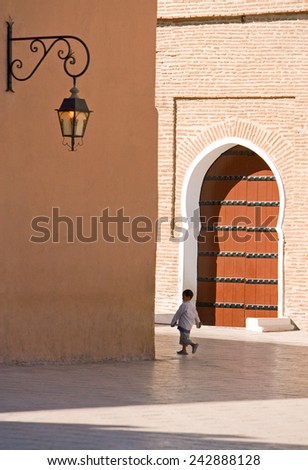 Marrakesh, Morocco - March 2006: A boy walking in front of the side door of the great Koutoubia mosque