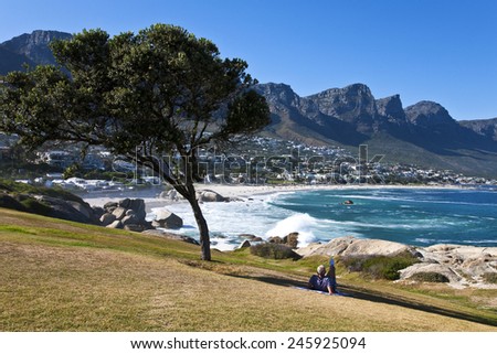 Cape town, South Africa - March 7 2010: A man lying in the shade looks at the beautiful seascape of Clifton Bay