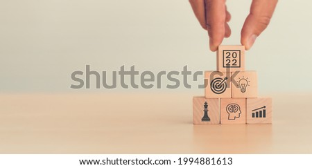 Business goal 2022. Hand pick up wood cubes with icon business strategy, action plan, goal, increase sale, process, game plan, copy space, blue background Business development Achieving business goal.