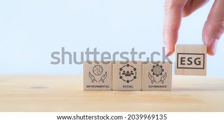 ESG concept of environmental, social and governance. Sustainable and ethical business.Businessman holds wooden cube with text "ESG" surrounding with ESG icon on beautiful white background. Copy space
